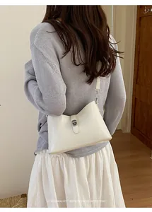 Sofisticata borsa sottobraccio color crema abbinata a maglia grigia e gonna bianca