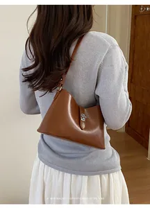 Modella indossa borsa sottobraccio in pelle marrone con fibbia argento retrò