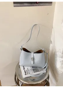 Borsa sottobraccio azzurra minimalista su uno sgabello per un look rétro sofisticato