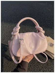 Vue détaillée d'un sac à main rose clair avec poignée nouée et bandoulière réglable