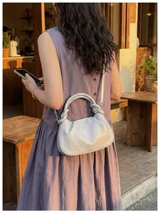 Vue détaillée du sac à main gris tendance porté par un mannequin en extérieur
