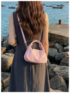 Vue de dos détaillée d'une femme portant un sac à main rose élégant en bord de mer