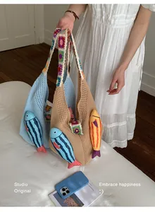 Vista detallada del bolso tote tejido con temática marina y colgantes de peces a mano