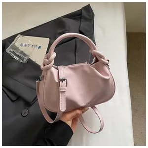 Détail d'un sac à main rose de luxe sur fond de costume gris élégant.