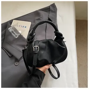 Vue détaillée du sac à main noir froncé avec boucle argentée et une poignée ronde moderne.