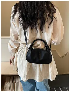 Sac à main élégant noir en forme de boulette porté en bandoulière par le modèle dos
