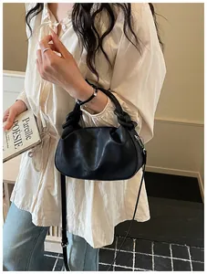 Vue détaillée d'un sac à main noir plissé avec poignée nouée et bandoulière