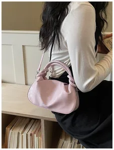 Gros plan d'un sac à main plissé rose porté par un mannequin dans un cadre chic.