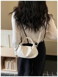 Vue détaillée d'un sac à bandoulière blanc plissé en forme de ravioli porté par un mannequin