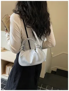 Détail d'un sac à main argenté en forme de boulette porté en bandoulière par un mannequin.