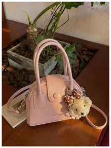 Detailweergave van roze lederen handtas met schattige berenhanger op houten tafel