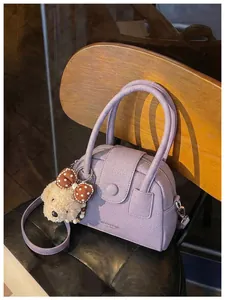 Detailopname van een paarse tas van kiezelleder met een schattige hondenhanger