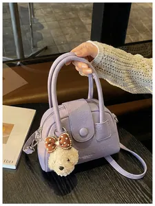Detailopname van een lavendelkleurige handtas met een schattige berenbedel in een café