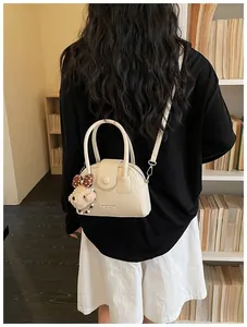 Stijlvolle beige handtas van gekorreld leer met een schattige berenhanger voor dames.