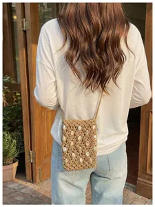 Bolso bandolera de paja tejido a mano para móvil con detalles de conchas para verano.