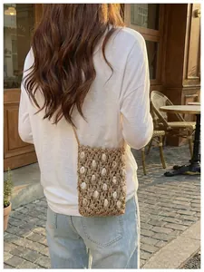 Bolso bandolera de paja tejida para móvil con conchas, mostrado en modelo en café