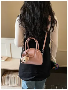 Achteraanzicht van model met een roze getextureerde kussen-handtas met een beer hanger