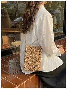 Vista lateral de bolso de paja para móvil con detalles de conchas para la playa