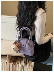 Gedetailleerd overzicht van een paarse kiezellederen kussenhandtas met een schattige teddybeer