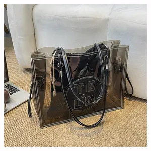Detailansicht einer rauchgrauen transparenten Tragetasche mit kreisförmigem Leder-Logo-Patch.