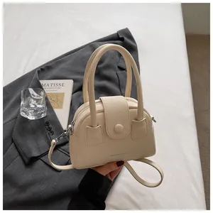 Detailweergave van beige kiezellederen handtas met ronde handvatten en riem