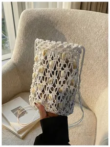Primer plano de un bolso para móvil de macramé blanco con cuentas decorativas de mármol