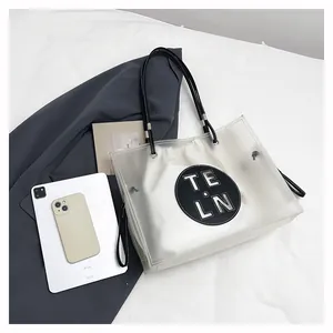 Nahaufnahme einer modischen transparenten PVC-Einkaufstasche mit schwarzem Logo-Patch