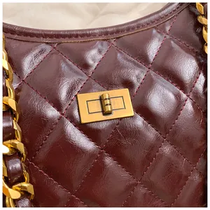 Detailed macro view of wine red quilted leather bag featuring vintage gold turn-lock