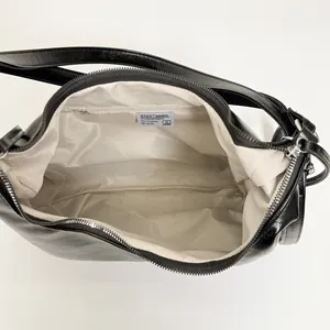 Dettaglio interno della borsa nera con fodera a spina di pesce e tasca con zip