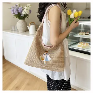 Handwoven straw tote bag with cute girl embroidery shown in a warm cafe lifestyle