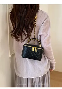 Elegant black quilted box handbag with a gold chain strap worn over the shoulder