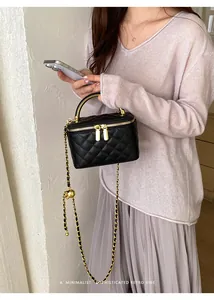 Detailed lifestyle view of a black quilted leather vanity box bag with gold chain strap