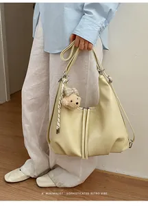 Vista dettagliata della borsa hobo crema indossata dal modello con ciondolo a orso