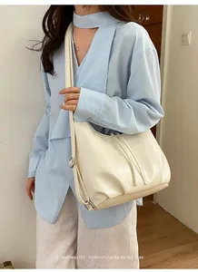 Borsa a tracolla minimalista bianco crema indossata in uno stile casual da pendolare