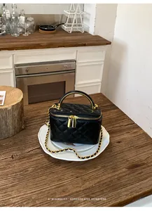 Detailed view of black quilted vanity bag with elegant gold hardware and chain