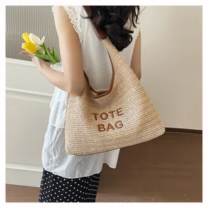 Close-up detail of handmade woven straw tote bag with TOTE BAG embroidery for beach