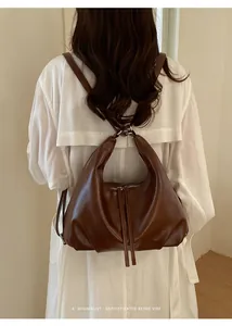 Dettaglio di uno zaino minimalista in pelle marrone su una modella con indosso un cappotto bianco
