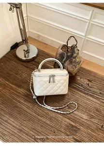 Elegant white quilted vanity box bag with silver chain strap on a rustic wooden table