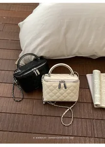 Close-up of black and cream quilted vanity bags with chain straps on wooden floor