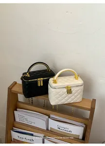 Elegant detail of quilted box handbags in black and white placed on a wooden magazine rack.