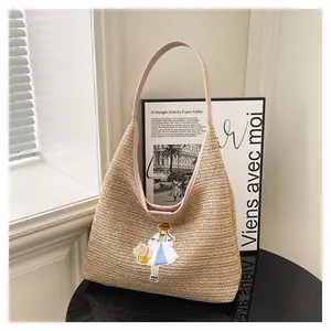 Detailed view of handmade woven straw tote bag with cute embroidery and pink strap