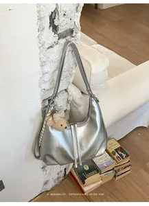 Dettaglio di una borsa hobo minimalista argento con un simpatico ciondolo orsetto.