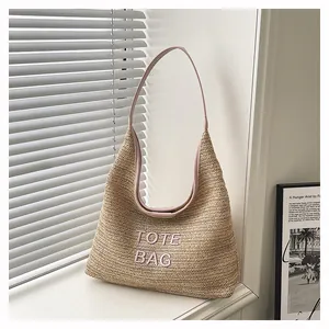 Large handmade woven straw tote bag for summer beach vacation with pink shoulder strap