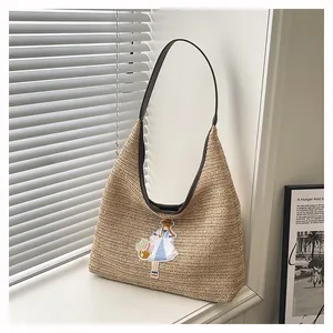 Handcrafted woven straw shoulder bag with cute girl embroidery detail on window sill