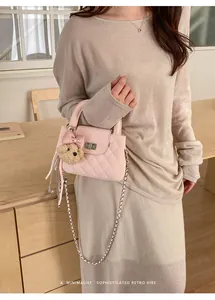 Detailed view of a pink quilted handbag with plush bear charm and elegant chain strap.