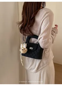 Back view of elegant black quilted handbag with chain strap on model's shoulder