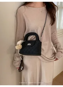 Close-up of black quilted handbag with chain strap and plush rabbit charm on model