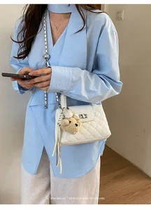 Elegant white quilted crossbody bag with a chain strap and cute teddy bear charm detail