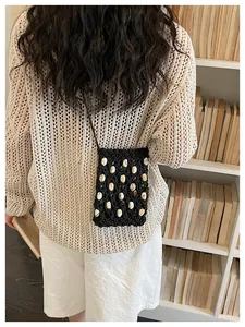 Bolso de ganchillo negro para móvil con detalles de caracolas en una biblioteca
