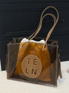 Stilvolle transparente PVC-Einkaufstasche mit brauner Innentasche und langen Riemen.